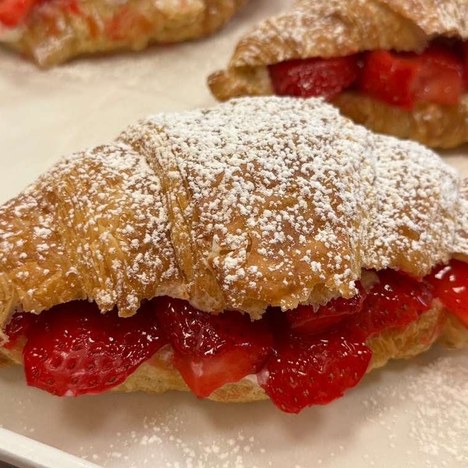 Croissants filled with fresh sliced strawberries and cream, dusted with powdered sugar